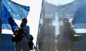 Una mujer pasa junto a las banderas de la UE situadas en el extrerior de la sede de la Comisión Europea, en Bruselas. AFP/Kenzo Tribouillard