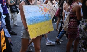 Una joven sostiene una pancarta en una manifestación por el clima para exigir un cambio en el sistema energético, en la Plaza Mayor, en Madrid (España).