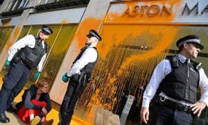Agentes de policía detienen a un activista después de que se arrojara pintura sobre la ventana de una sala de exposición de automóviles durante una protesta "Just Stop Oil" en Londres, Reino Unido, el 16 de octubre de 2022