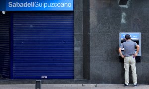 Un hombre opera en un cajero automático de una oficina de Banco Sabadell en la localidad  vasca de Guernica (Vizcaya). REUTERS/Vincent West