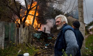 Varios residentes se paran cerca de una estructura en llamas después de un bombardeo en la ciudad de Bakhmut, en la región del Donbás, en el este de Ucrania, el 23 de octubre de 2022.