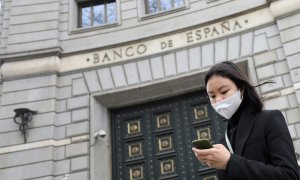 Una joven con mascarilla delante de la entrada del edificio del Banco de España en Barcelona. REUTERS/Nacho Doce
