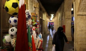 Una mujer camina, con el hiyab, por una calle de Catar decorada con banderas por el Mundial.