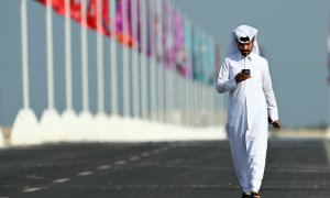 Un hombre pasea junto a las banderas de las selecciones que participan en el Mundial de fútbol de Catar