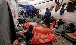 Migrantes intentan dormir en la cubierta del barco de rescate 'Ocean Viking' en el Mediterráneo a la espera de un puerto para desembarcar el pasado 6 de noviembre de 2022.