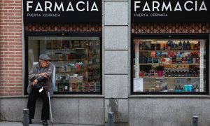 Un hombre mayor sentado en el escaparate de una farmacia en Madrid. REUTERS/Juan Medina