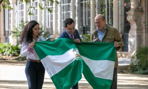 El presidente de la Junta de Andalucía, Juanma Moreno (c) entrega una bandera andaluza al creador del Reto Pelayo Vida, Eric Frattini (d) y a la expedicionaria almeriense Felisa Requena (i) antes de despedir a la expedición de la nueva edición.
