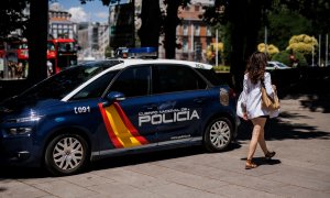 Una mujer pasa al lado de un coche de la Policía Nacional aparcado en el centro de la capital un día antes del inicio de la OTAN, a 27 de junio de 2022, en Madrid.