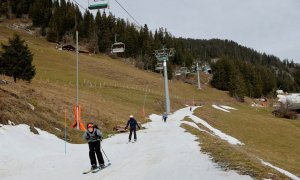 Esquiadores pasan sobre una pequeña capa de nieve en medio de temperaturas invernales más cálidas de lo habitual en los Alpes en Leysin, Suiza, a 4 de enero de 2023