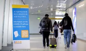 Viajeros de China pasan frente a una pancarta con información y reciben un test de covid-19 a su llegada a Schiphol, Países Bajos, el 04 de enero de 2023.