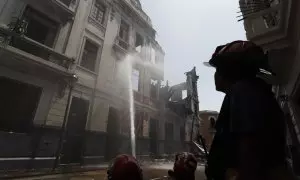 Bomberos trabajan en los alrededores de una casona que se incendió ayer durante la jornada de protestas en Lima.