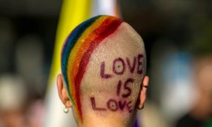 Imagen de archivo de una persona con los colores de la bandera LGBTI en la cabeza y el mensaje "Love is love".