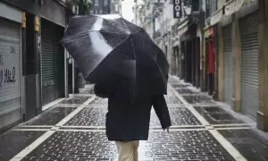 Un hombre camina protegiéndose con un paraguas por la lluvia por el casco viejo de Pamplona durante el Martes Santo a 7 de abril de 2020