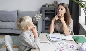 Una logopeda hace terapia del habla con un niño.