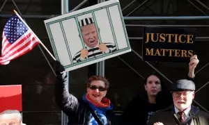 Manifestantes sostienen una imagen que muestra a Trump tras las rejas y un cartel que dice "La justicia importa" durante una protesta contra el ex presidente estadounidense Trump frente a un tribunal.