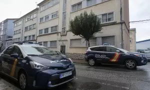 Dos vehículos de Policía Nacional aparcados frente a unos edificios.