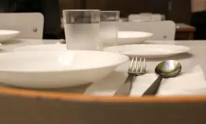 Pla detall d'un plat i els coberts en un menjador escolar