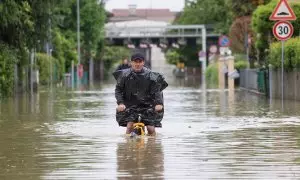 Un hombre monta en bicicleta en mitad de las inundaciones provocadas por las lluvias torrenciales de mayo en Emilia-Romagna, en Italia.
