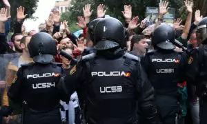 Pla mig d'agents de la policia espanyola d'esquenes intentant impedir el pas de ciutadans que feien cua per votar a l'Escola Ramon Llull, l'1 d'octubre de 2017