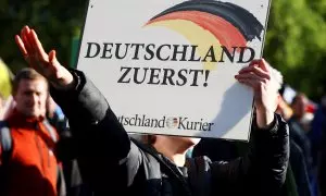 Un seguidor de la formación ultra alemana AfD sujeta una pancarta con el lema "Alemanes primero" y realiza el saludo fascista, en Berlín, a 8 de octubre de 2022.