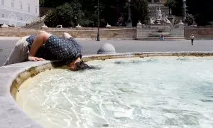 Una mujer sumerge su cabeza en el agua de la Piazza del Popolo, en Roma, para hacer frente al calor extremo que sacude a Italia.
