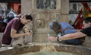 Varias personas se refrescan en una fuente en la localidad valenciana de Xàtiva