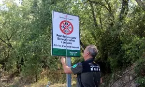 Un Agent Rural obre un cartell de prohibició del pas al Montsec a la zona de Corçà, a Àger, per l'activació del pla Alfa 3