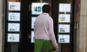 Una dona revisa les ofertes de pisos a la venda fora d'una immobiliària