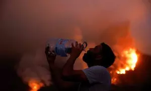 Un hombre bebe agua cerca de las llamas del incendio de Tenerife, en las Islas Canarias, España.