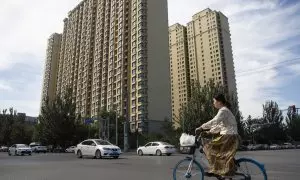 Una mujer pasa en bicicleta por un complejo de viviendas de Evergrande en Pekín. EFE/EPA/ANDRÉS MARTÍNEZ CASARES