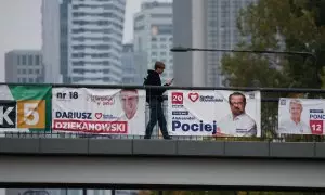 Un hombre camina cerca de carteles electorales exhibidos en el centro de la ciudad de Varsovia, antes de las elecciones parlamentarias del domingo.