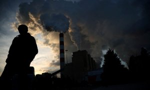 Un hombre camina mientras el humo y el vapor se elevan desde la central eléctrica de Belchatow, la central eléctrica alimentada por carbón y lignito más grande de Europa.