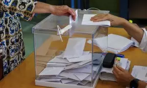Una mujer introduce su voto en una urna en un colegio electoral.