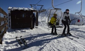 Dos personas se bajan del telesilla en la estación de esquí de Puerto de Navacerrada.