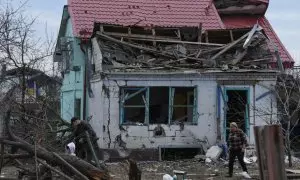 Varios vecinos caminan entre los escombros de una casa tras un ataque ruso en Ucrania.