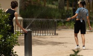 Dos jóvenes se mojan con una fuente de Plaza España, a 16 de junio de 2022, en Madrid.