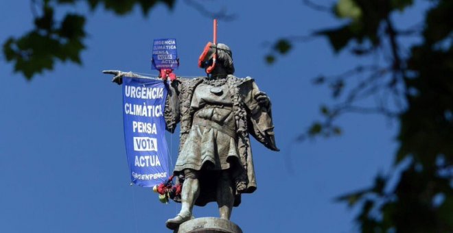 Dos activistas de Greenpeace colocan unas gafas de buzo a la estatua de Colón