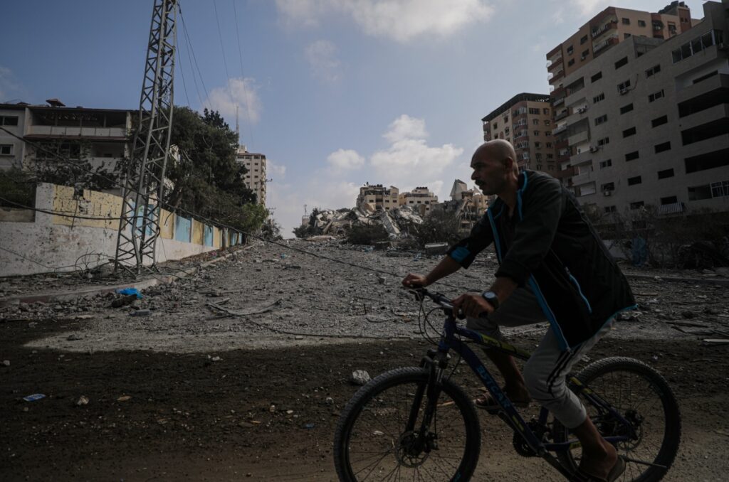 Un hombre palestino pasa en bicicleta por una carretera destruida tras los ataques aéreos israelíes en la ciudad de Gaza. EFE/EPA/MOHAMMED SABER
