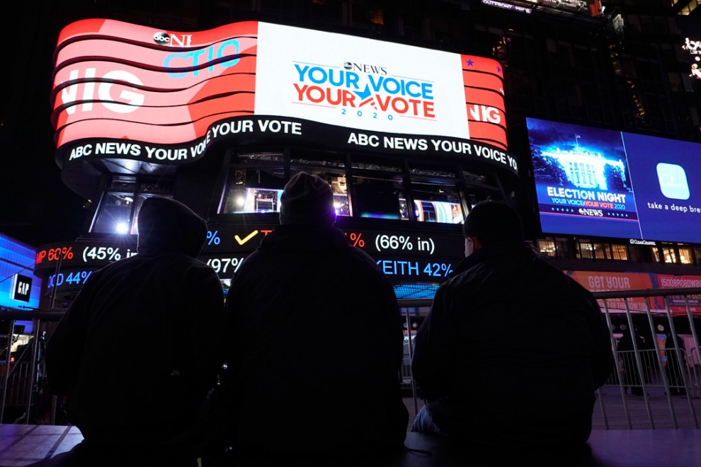 Varias personas observan cómo va el recuento de votos en Times Square, Nueva York.