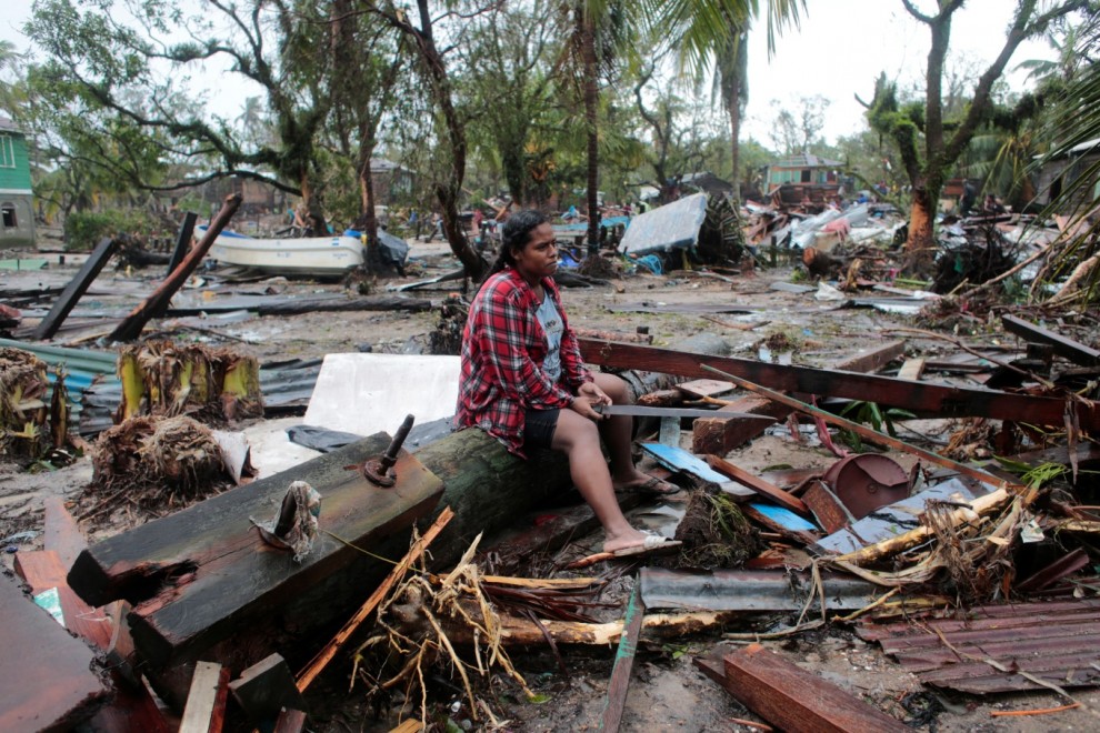 Una mujer está sentada en un poste de luz derribado mientras contempla su casa destruida tras el paso del huracán Iota, en Puerto Cabezas, Nicaragua.