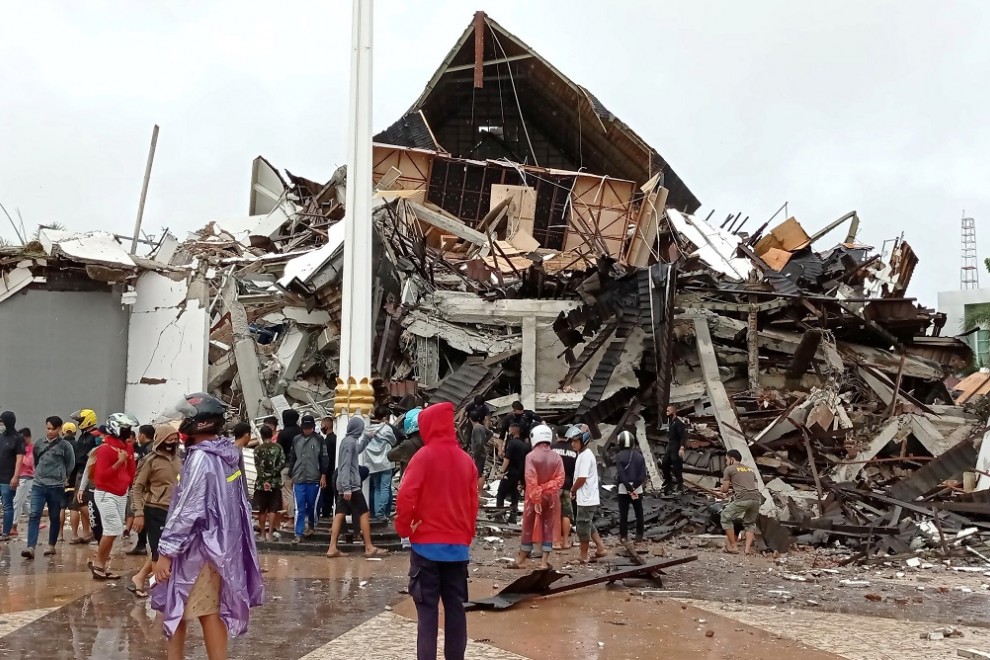 Algunas personas miran los restos de la oficina del gobernador arrasada por el terremoto en la ciudad de Mamuju, Indonesia.