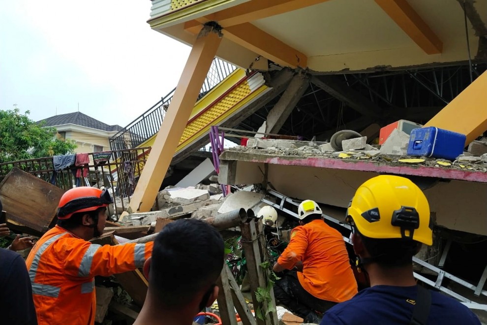 Miembros de los servicios de emergencias buscan supervivientes entre los escombros de un edificio en la ciudad de Mamuju, Indonesia.