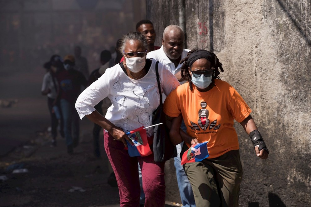 Personas corren para protegerse durante una jornada de protesta contra el Gobierno de Jovenel Moise hoy, en Puerto Príncipe (Haití).