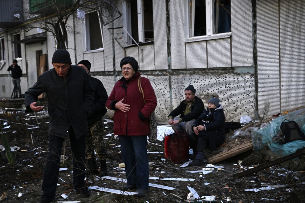 Varias personas junto a un edificio destruido por los bombardeos en la ciudad de Chuguiv, en el este de Ucrania, este 24 de febrero.