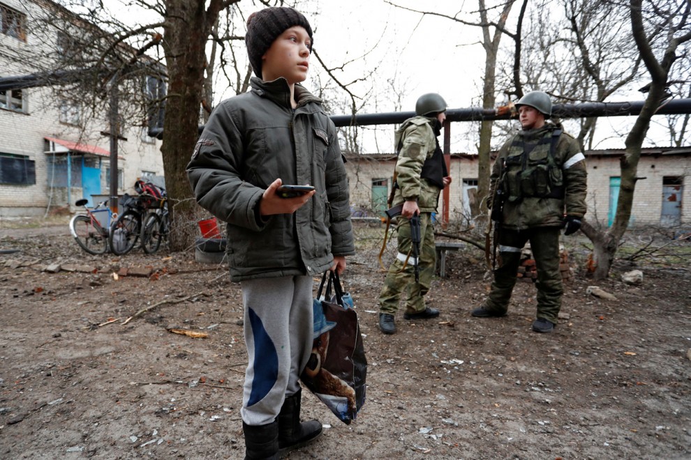 Un niño se para frente a un edificio de apartamentos, que según los lugareños fue dañado por los recientes bombardeos, en la ciudad de Yasynuvata (Yasinovataya), controlada por los separatistas prorrusos, en la región de Donetsk, Ucrania, este jueves.