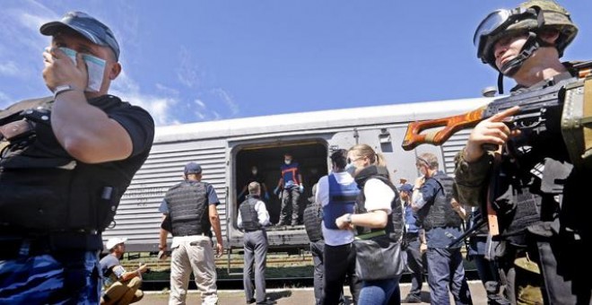 Un soldado separatista ucraniano (izq) se cubre la nariz junto a un vagón de tren en el que se transportan los cadáveres de las víctimas.