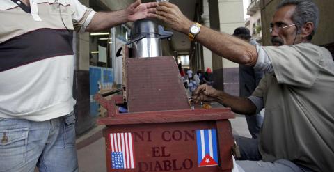 Un hombre vende café en un puesto callejero de La Habana decorado con las banderas de EEUU y Cuba. REUTERS