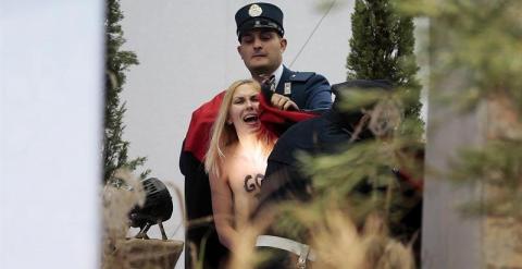 Un miembro de la gendarmería vaticana cubre y detiene a una activista de Femen que intentó llevarse la figura del niño Jesús del belén instalado en la Plaza de San Pedro del Vaticano, este jueves 25 de diciembre de 2014.  EFE