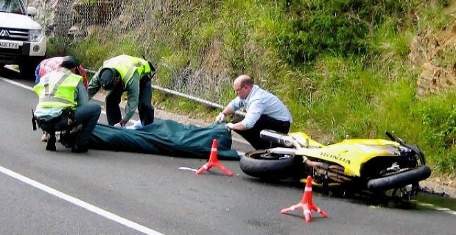 Miembros de la Guardia Civil de Tráfico y del servicio de emergencias se disponen al traslado de una de las tres víctimas mortales, tres motoristas, que fallecieron hoy en el accidente de tráfico registrado en el kilómetro 16 de la carretera AS-15, en el 