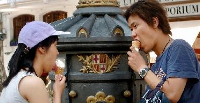 Dos turistas se refrescan en la Fuente de Canaletas, en las Ramblas de Barcelona.